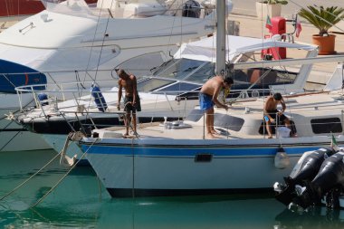 İtalya, Sicilya, Akdeniz, Marina di Ragusa (Ragusa ili); 6 Ağustos 2024, limandaki bir yelkenli teknesinde erkekler - EDITORIA