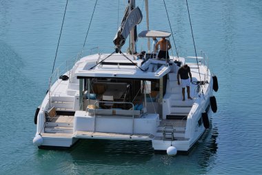 İtalya, Sicilya, Akdeniz, Marina di Ragusa (Ragusa ili); 10 Ağustos 2024, limandaki katamaran yelkenli teknesinde erkekler - EDITORIAL