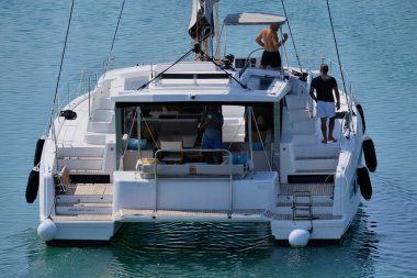 İtalya, Sicilya, Akdeniz, Marina di Ragusa (Ragusa ili); 10 Ağustos 2024, limandaki katamaran yelkenli teknesinde erkekler - EDITORIAL