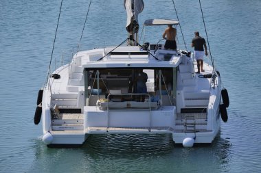 İtalya, Sicilya, Akdeniz, Marina di Ragusa (Ragusa ili); 10 Ağustos 2024, limandaki katamaran yelkenli teknesinde erkekler - EDITORIAL