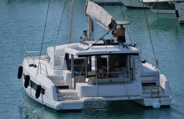 İtalya, Sicilya, Akdeniz, Marina di Ragusa (Ragusa ili); 10 Ağustos 2024, limandaki katamaran yelkenli teknesinde erkekler - EDITORIAL