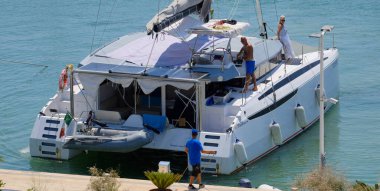 İtalya, Sicilya, Akdeniz, Marina di Ragusa (Ragusa Eyaleti); 11 Ağustos 2024, limanda bir katamaran yelkenli teknesinde çift