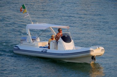 İtalya, Sicilya, Akdeniz, Marina di Ragusa (Ragusa Eyaleti); 11 Ağustos 2024, gün batımında büyük bir kauçuk teknede adamlar - EDITORIAL