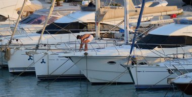 İtalya, Sicilya, Akdeniz, Marina di Ragusa (Ragusa Eyaleti); 16 Ağustos 2024, limanda lüks bir yatta adam - EDITORIAL