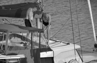 İtalya, Sicilya, Akdeniz, Marina di Ragusa (Ragusa ili); 19 Ağustos 2024, limanda bir katamaran yelkenli teknesini temizleyen adamlar - EDITORIAL