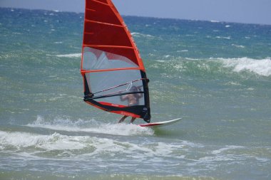 İtalya, Sicilya, Akdeniz, Donnalucata (Ragusa Eyaleti); 20 Ağustos 2024, dalgalara binen sörfçü - EDITORIAL