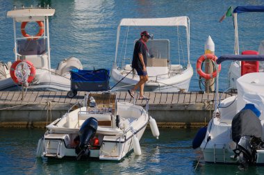 İtalya, Sicilya, Akdeniz, Marina di Ragusa (Ragusa ili); 22 Ağustos 2024, limandaki insanlar, motorlu tekneler ve lüks yatlar - EDITORIAL