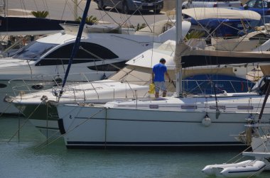 İtalya, Sicilya, Akdeniz, Marina di Ragusa (Ragusa Eyaleti); 25 Ağustos 2024, limandaki bir yelkenli ve lüks yatlarda adam - EDITORIAL