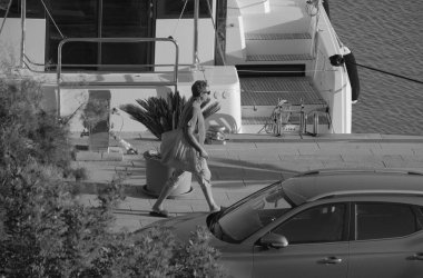 İtalya, Sicilya, Akdeniz, Marina di Ragusa (Ragusa Eyaleti); limanda bir adam ve bir katamaran yelkenli teknesi 