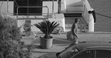 İtalya, Sicilya, Akdeniz, Marina di Ragusa (Ragusa Eyaleti); limanda bir adam ve bir katamaran yelkenli teknesi 