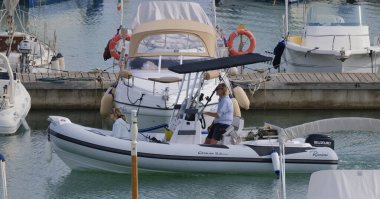 İtalya, Sicilya, Akdeniz, Marina di Ragusa (Ragusa Eyaleti); 19 Eylül 2024, limanda kauçuk bir tekne ve lüks yatlarda bir çift - EDITORIAL