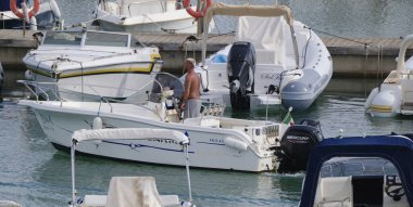 İtalya, Sicilya, Akdeniz, Marina di Ragusa (Ragusa Eyaleti); 19 Eylül 2024, limandaki bir motorlu teknede adam - EDITORIAL