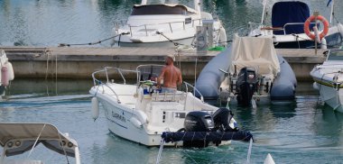 İtalya, Sicilya, Akdeniz, Marina di Ragusa (Ragusa Eyaleti); 19 Eylül 2024, limandaki bir motorlu teknede adam - EDITORIAL