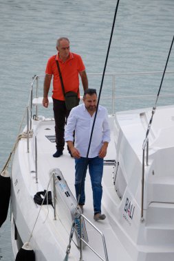 İtalya, Sicilya, Akdeniz, Marina di Ragusa (Ragusa Eyaleti); 22 Eylül 2024, limandaki bir katamaran yelkenli teknesinde erkekler - EDITORIAL