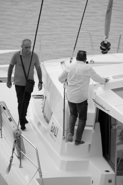 İtalya, Sicilya, Akdeniz, Marina di Ragusa (Ragusa Eyaleti); 22 Eylül 2024, limandaki bir katamaran yelkenli teknesinde erkekler - EDITORIAL