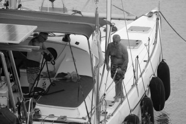 İtalya, Sicilya, Akdeniz, Marina di Ragusa (Ragusa Eyaleti); 22 Eylül 2024, limandaki bir katamaran yelkenli teknesinde erkekler - EDITORIAL