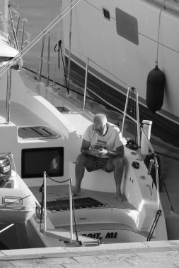 İtalya, Sicilya, Akdeniz, Marina di Ragusa (Ragusa Eyaleti); 1 Ekim 2024, limandaki bir katamaran yelkenli teknesinde adam - EDITORIAL