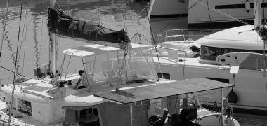 İtalya, Sicilya, Akdeniz, Marina di Ragusa (Ragusa Eyaleti); 2 Ekim 2024, insan ve limanda bir katamaran yelkenli teknesi - EDITORIAL