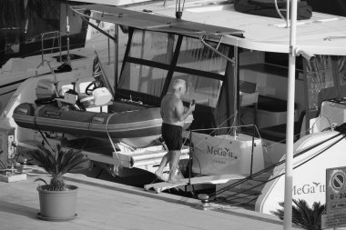 İtalya, Sicilya, Akdeniz, Marina di Ragusa (Ragusa Eyaleti); 3 Ekim 2024, limandaki bir katamaran yelkenli teknesinde adam - EDITORIAL