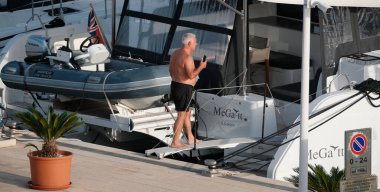 İtalya, Sicilya, Akdeniz, Marina di Ragusa (Ragusa Eyaleti); 3 Ekim 2024, limandaki bir katamaran yelkenli teknesinde adam - EDITORIAL