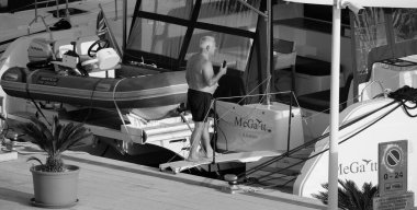 İtalya, Sicilya, Akdeniz, Marina di Ragusa (Ragusa Eyaleti); 3 Ekim 2024, limandaki bir katamaran yelkenli teknesinde adam - EDITORIAL