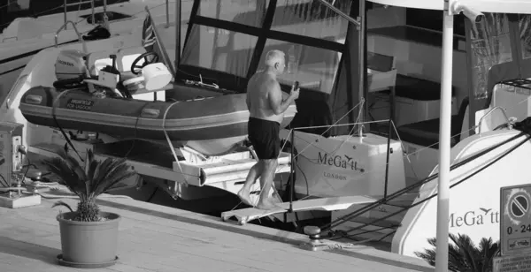 İtalya, Sicilya, Akdeniz, Marina di Ragusa (Ragusa Eyaleti); 3 Ekim 2024, limandaki bir katamaran yelkenli teknesinde adam - EDITORIAL