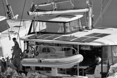 İtalya, Sicilya, Akdeniz, Marina di Ragusa (Ragusa Eyaleti); 7 Ekim 2024, limandaki katamaran yelkenli teknesinde insanlar - EDITORIAL