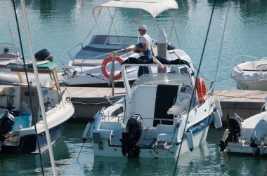 İtalya, Sicilya, Akdeniz, Marina di Ragusa (Ragusa ili); 9 Kasım 2024, limandaki insanlar, motorlu tekneler ve lüks yatlar - EDITORIAL