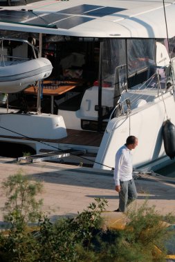 İtalya, Sicilya, Akdeniz, Marina di Ragusa (Ragusa Eyaleti); 14 Kasım 2024; limanda bir insan ve bir katamaran yelkenli teknesi - EDITORIAL