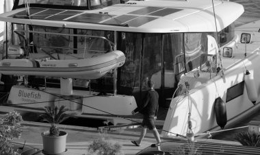 İtalya, Sicilya, Akdeniz, Marina di Ragusa (Ragusa Eyaleti); 22 Kasım 2024, limanda insanlar ve bir katamaran yelkenli teknesi - EDITORIAL