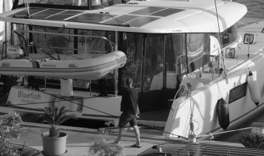 İtalya, Sicilya, Akdeniz, Marina di Ragusa (Ragusa Eyaleti); 22 Kasım 2024, limanda insanlar ve bir katamaran yelkenli teknesi - EDITORIAL