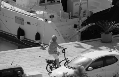 İtalya, Sicilya, Akdeniz, Marina di Ragusa (Ragusa Eyaleti); 23 Kasım 2024, limanda bir bisiklet ve katamaran yelkenli teknesi - EDITORIAL