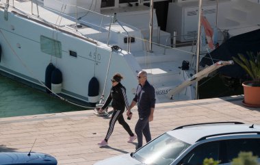 İtalya, Sicilya, Akdeniz, Marina di Ragusa (Ragusa ili); 24 Kasım 2024, çift ve limanda bir katamaran yelkenli teknesi - EDITORIAL