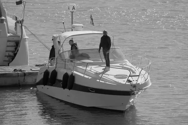 İtalya, Sicilya, Akdeniz, Marina di Ragusa (Ragusa Eyaleti); 24 Kasım 2024, limanda lüks bir yatta erkekler - EDITORIAL