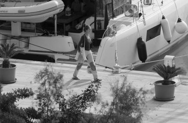 İtalya, Sicilya, Akdeniz, Marina di Ragusa (Ragusa Eyaleti); 26 Kasım 2024, kadın ve limanda bir katamaran yelkenli teknesi - EDITORIAL