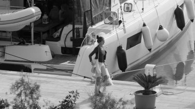 İtalya, Sicilya, Akdeniz, Marina di Ragusa (Ragusa Eyaleti); 26 Kasım 2024, kadın ve limanda bir katamaran yelkenli teknesi - EDITORIAL