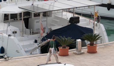 İtalya, Sicilya, Akdeniz, Marina di Ragusa (Ragusa Eyaleti); 26 Kasım 2024, limanda insanlar ve katamaran yelkenli tekneleri - EDITORIAL