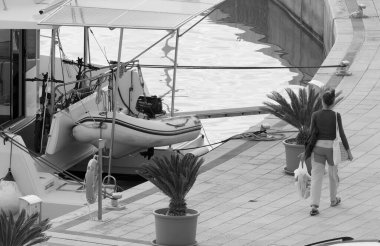 İtalya, Sicilya, Akdeniz, Marina di Ragusa (Ragusa Eyaleti); 26 Kasım 2024, kadın ve limanda bir katamaran yelkenli teknesi - EDITORIAL