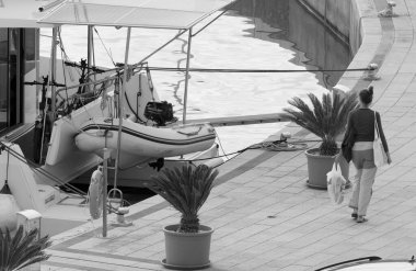 İtalya, Sicilya, Akdeniz, Marina di Ragusa (Ragusa Eyaleti); 26 Kasım 2024, kadın ve limanda bir katamaran yelkenli teknesi - EDITORIAL