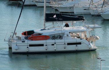 İtalya, Sicilya, Akdeniz, Marina di Ragusa (Ragusa Eyaleti); 27 Kasım 2024, limandaki bir katamaran yelkenli teknesinde adam - EDITORIAL