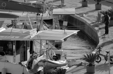 İtalya, Sicilya, Akdeniz, Marina di Ragusa (Ragusa Eyaleti); 27 Kasım 2024, limandaki bir katamaran yelkenli teknesinde adam - EDITORIAL