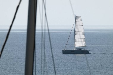 İtalya, Sicilya, Akdeniz; insanlar Sicilya Kanalı 'nda katamaran yelkenliyle yelken açıyor.