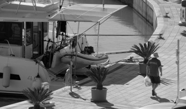 İtalya, Sicilya, Akdeniz, Marina di Ragusa (Ragusa Eyaleti); 3 Aralık 2024, insan ve limanda bir katamaran yelkenli teknesi - EDITORIAL