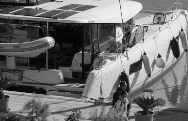 İtalya, Sicilya, Akdeniz, Marina di Ragusa (Ragusa ili); 3 Aralık 2024, çift ve limanda bir katamaran yelkenli teknesi - EDITORIAL