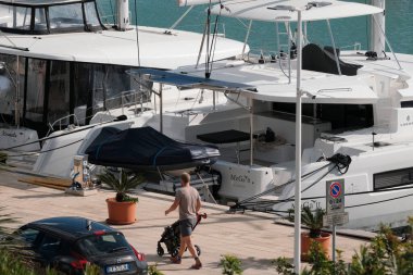 İtalya, Sicilya, Akdeniz, Marina di Ragusa (Ragusa ili); 16 Aralık 2024, limanda insanlar ve katamaran yelkenli tekneleri - EDITORIAL