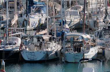 İtalya, Sicilya, Akdeniz, Marina di Ragusa (Ragusa ili); 18 Aralık 2024, limandaki insanlar ve yelkenliler - EDITORIAL