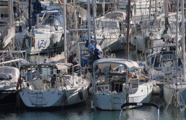 İtalya, Sicilya, Akdeniz, Marina di Ragusa (Ragusa ili); 18 Aralık 2024, limandaki insanlar ve yelkenliler - EDITORIAL