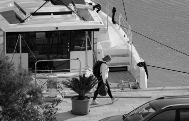 İtalya, Sicilya, Akdeniz, Marina di Ragusa (Ragusa Eyaleti); 20 Aralık 2024, kadın ve limanda bir katamaran yelkenli teknesi - EDITORIAL