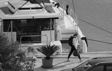 İtalya, Sicilya, Akdeniz, Marina di Ragusa (Ragusa Eyaleti); 20 Aralık 2024, kadın ve limanda bir katamaran yelkenli teknesi - EDITORIAL