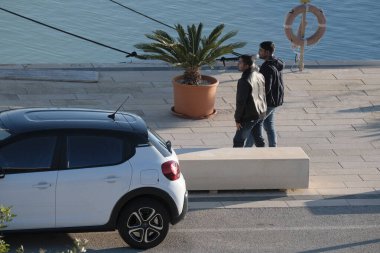 Italy, Sicily, Marina di Ragusa (Ragusa Province); 22 December 2024, men relaxing on a bench in the port - EDITORIAL clipart